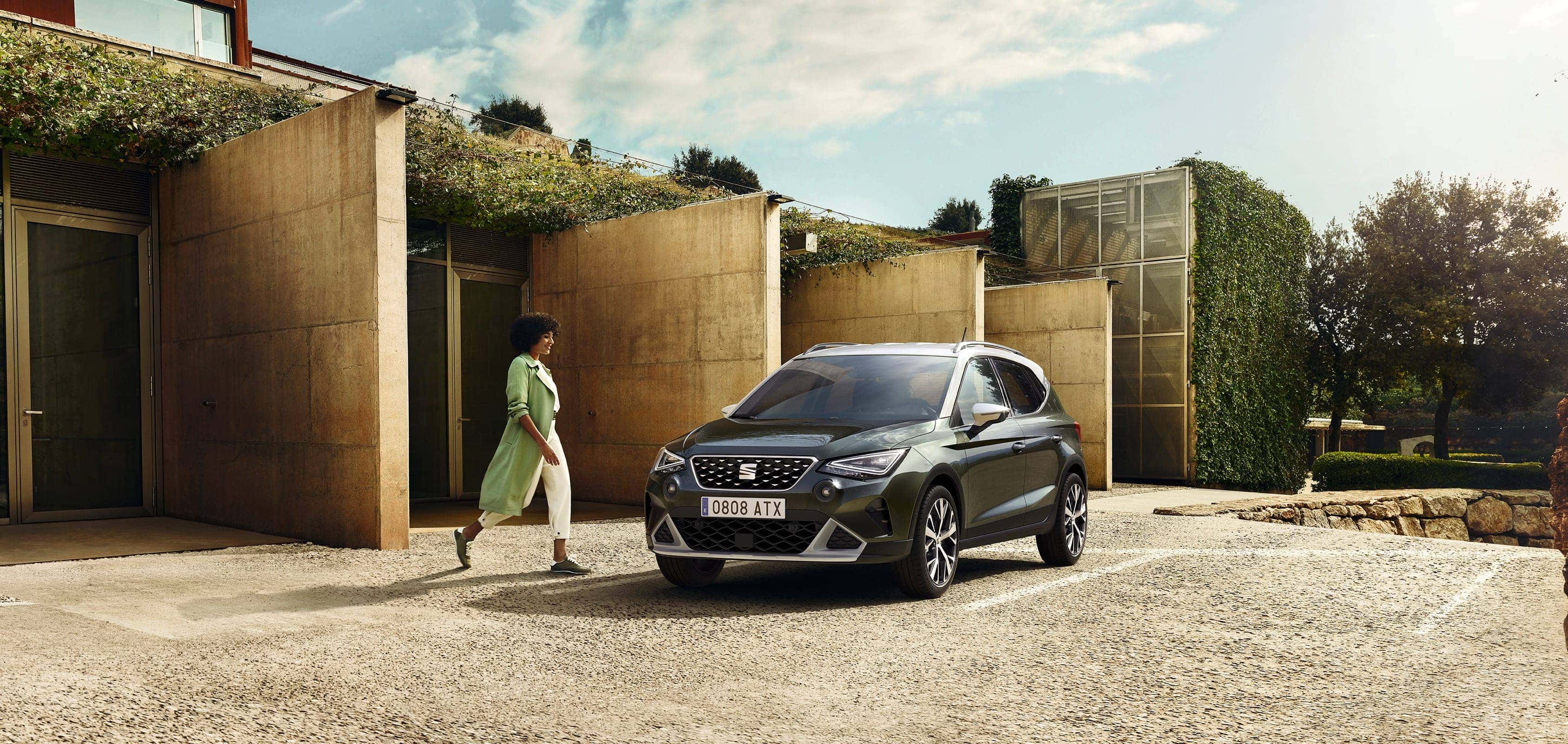 Femme marche jusqu’à SEAT Arona couleur camouflage foncé avec toit blanc bonbon