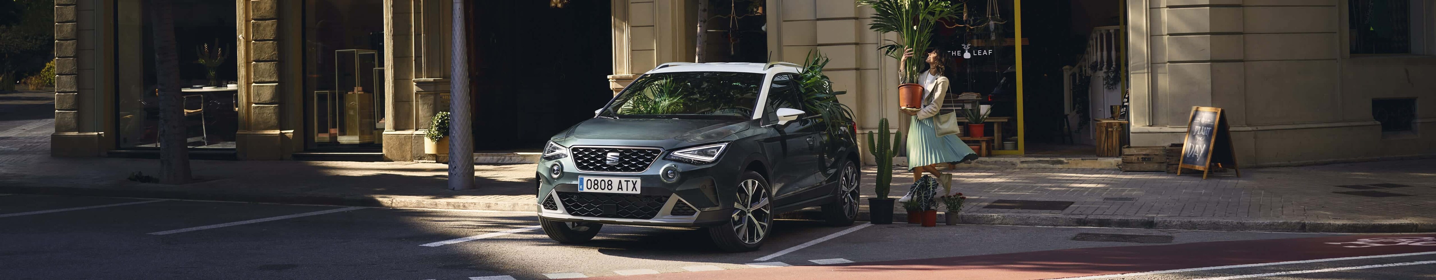 Femme avec une plante marche à SEAT arona couleur camouflage foncé