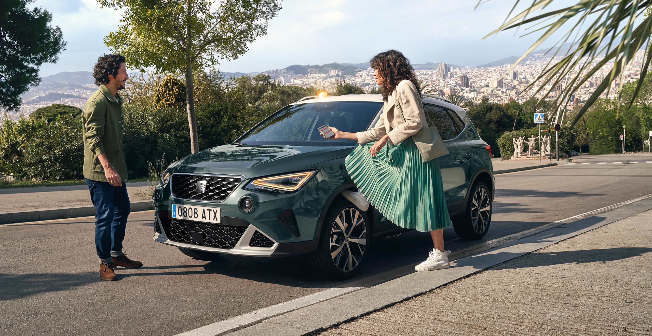 Femme avec le pied sur la roue de SEAT Arona regardant son smartphone