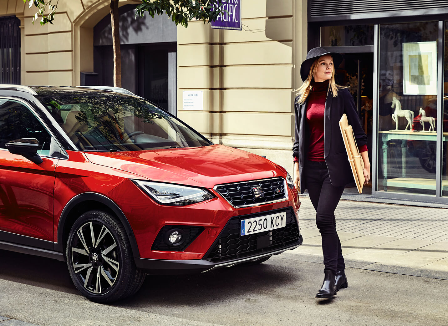 SEAT new car services and maintenance – Woman walking in front of a SEAT Arona crossover SUV